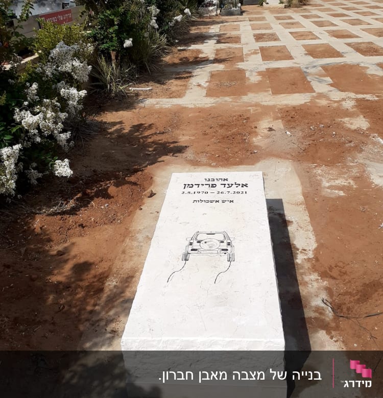 מצבה לבנה עם כיתוב וציור של רכב